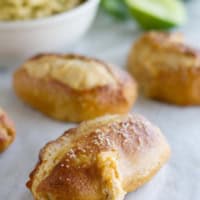 Jalapeno Stuffed Taco Soft Pretzel Sticks on parchment with guacamole for dipping in the background.