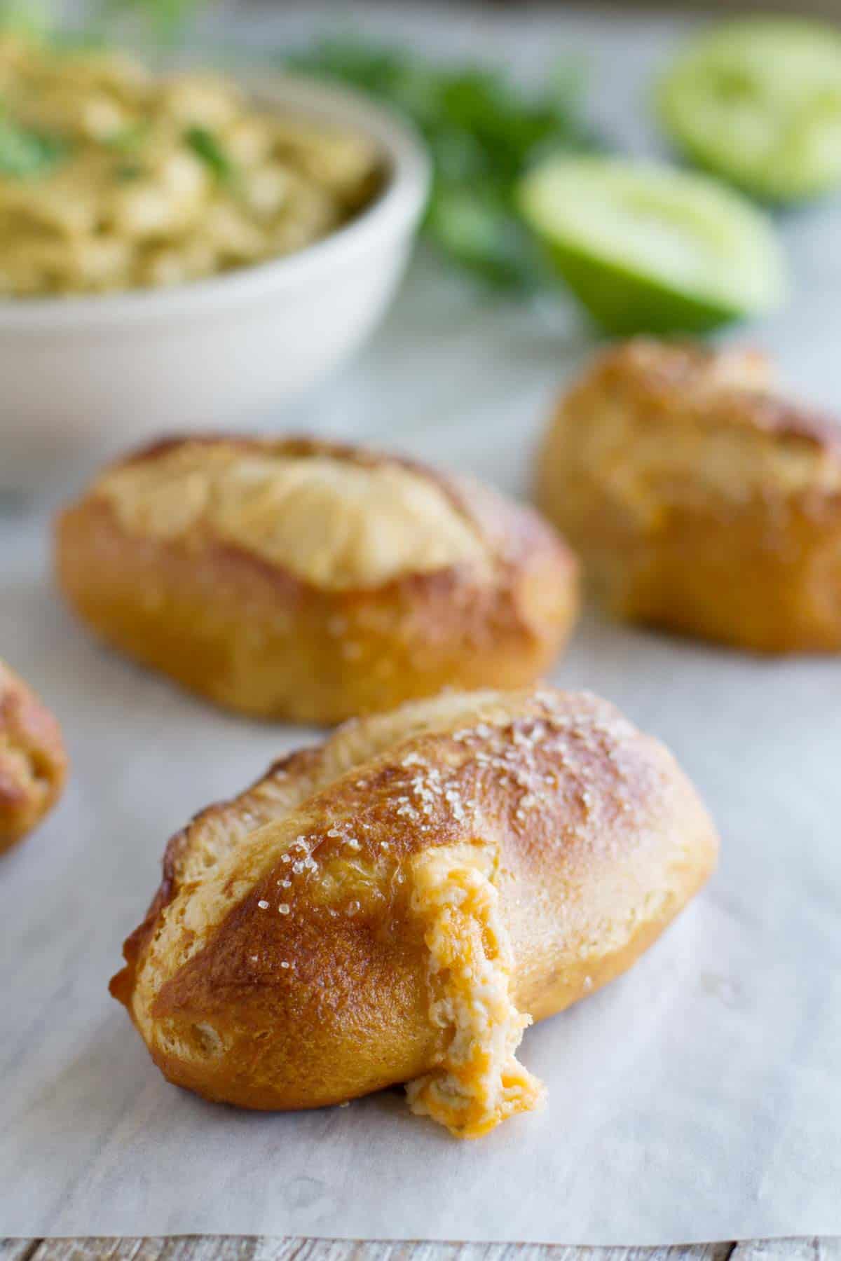 Jalapeno Stuffed Taco Soft Pretzel Sticks on parchment with guacamole for dipping in the background.