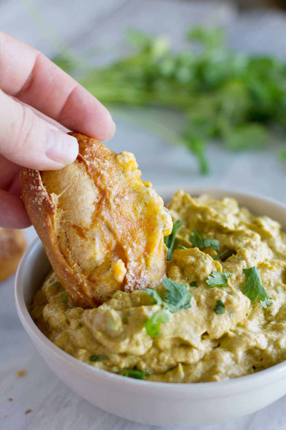 Dunking a jalapeno stuffed taco soft pretzel stick into guacamole.