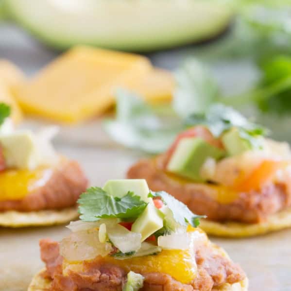 Nacho bites with a tortilla chip topped with refried beans, cheese, and toppings.