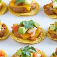 Nacho bites topped with cilantro, avocado, and pico de gallo.