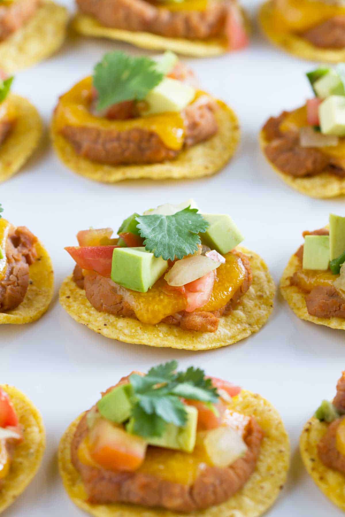 Nacho bites topped with cilantro, avocado, and pico de gallo.