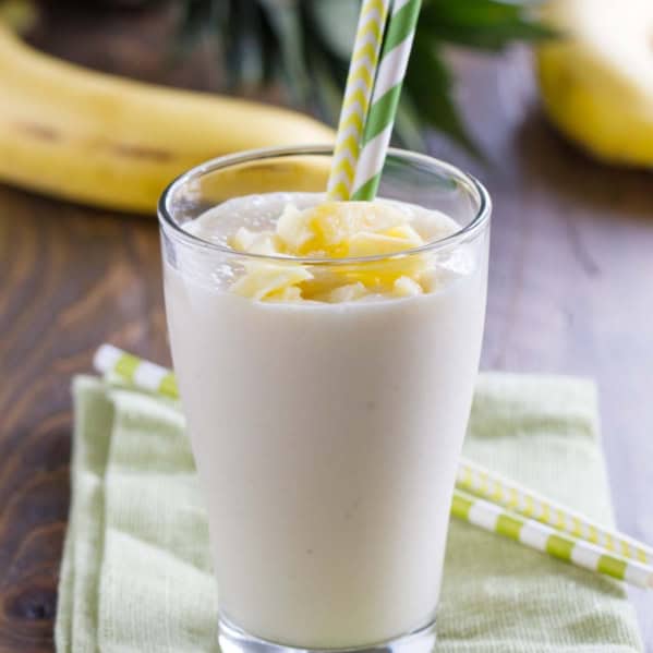 Pineapple Banana Smoothie in a glass with two straws.