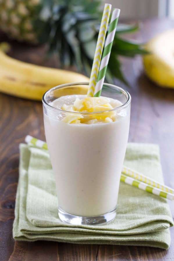 Pineapple Banana Smoothie in a glass with two straws.