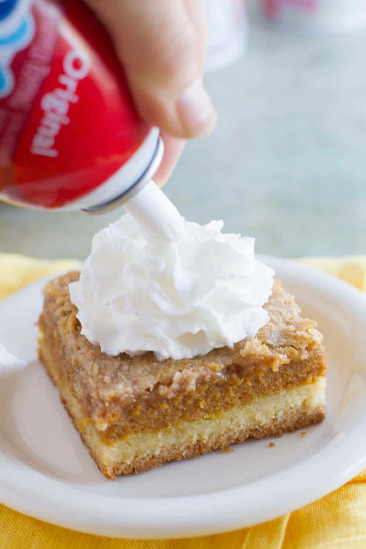 Adding Reddi-Wip to the top of a slice of Pumpkin Pie Cake.