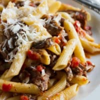 Slow Simmered Short Rib Sauce with Pasta on a plate, with freshly grated parmesan on top.