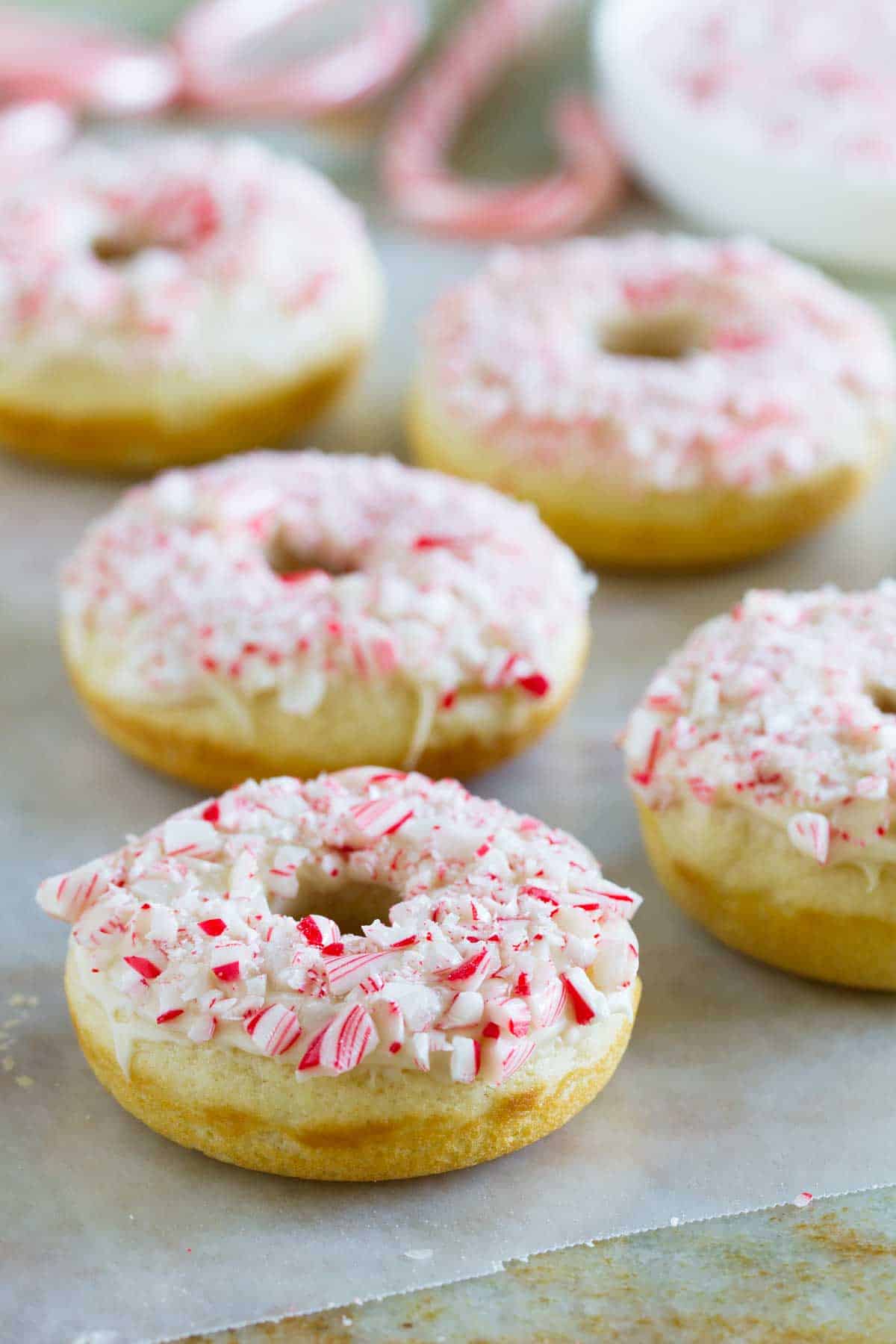 Baked Peppermint Donuts topped with glaze and crushed candy canes.