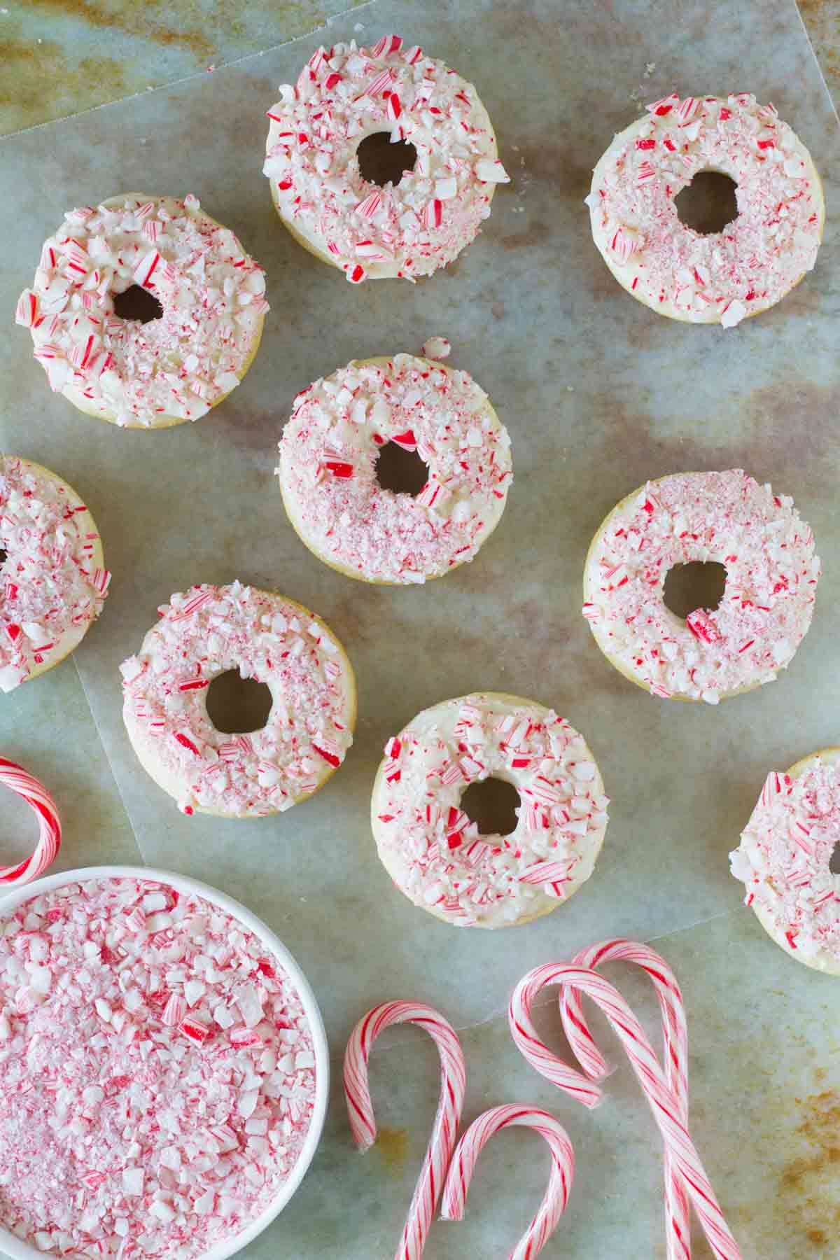 Baked Peppermint Donuts with crushed candy canes and full candy canes on the side.