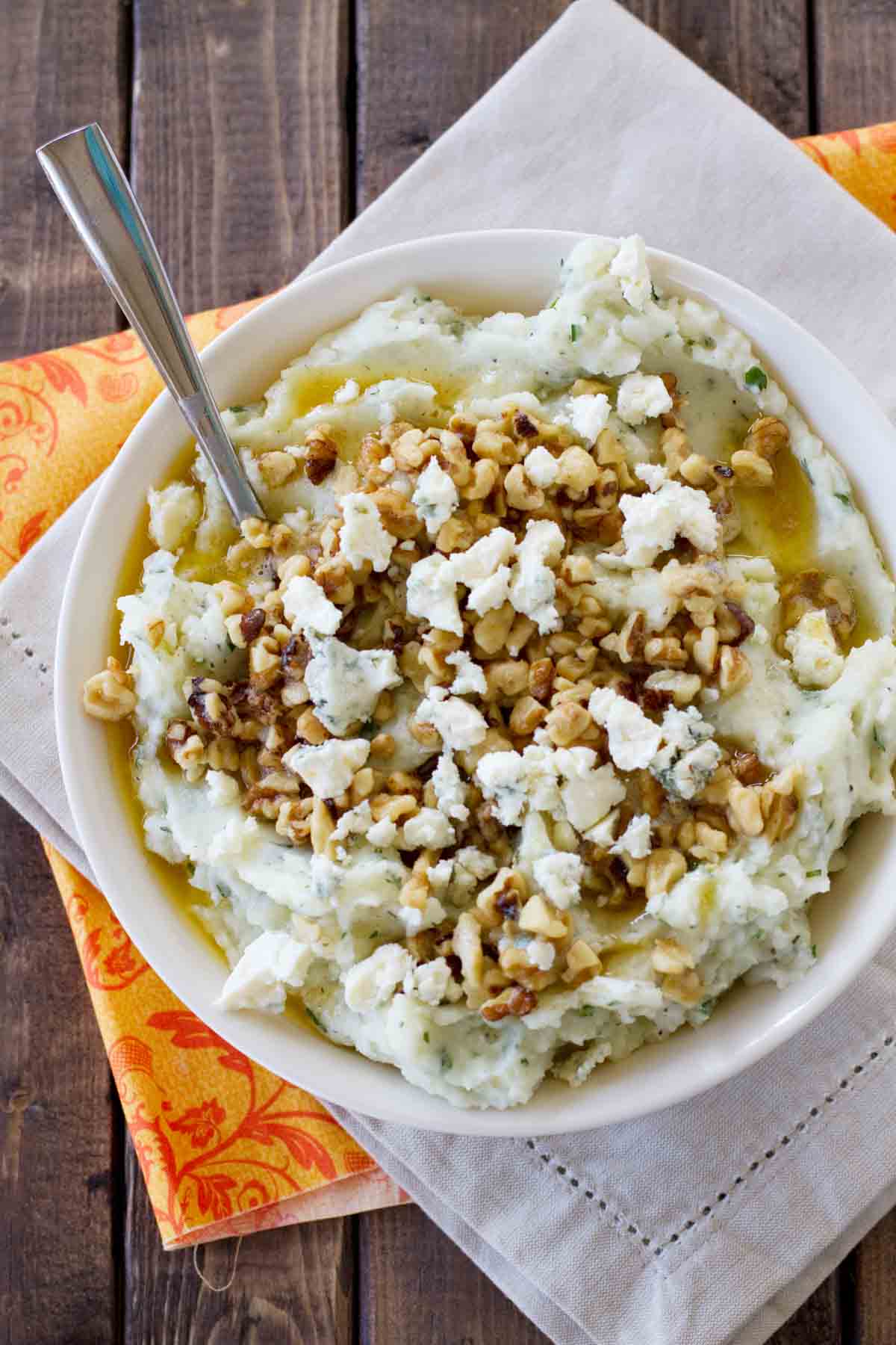 Bowl filled with Blue Cheese and Walnut Mashed Potatoes topped with walnuts, blue cheese, and brown butter.