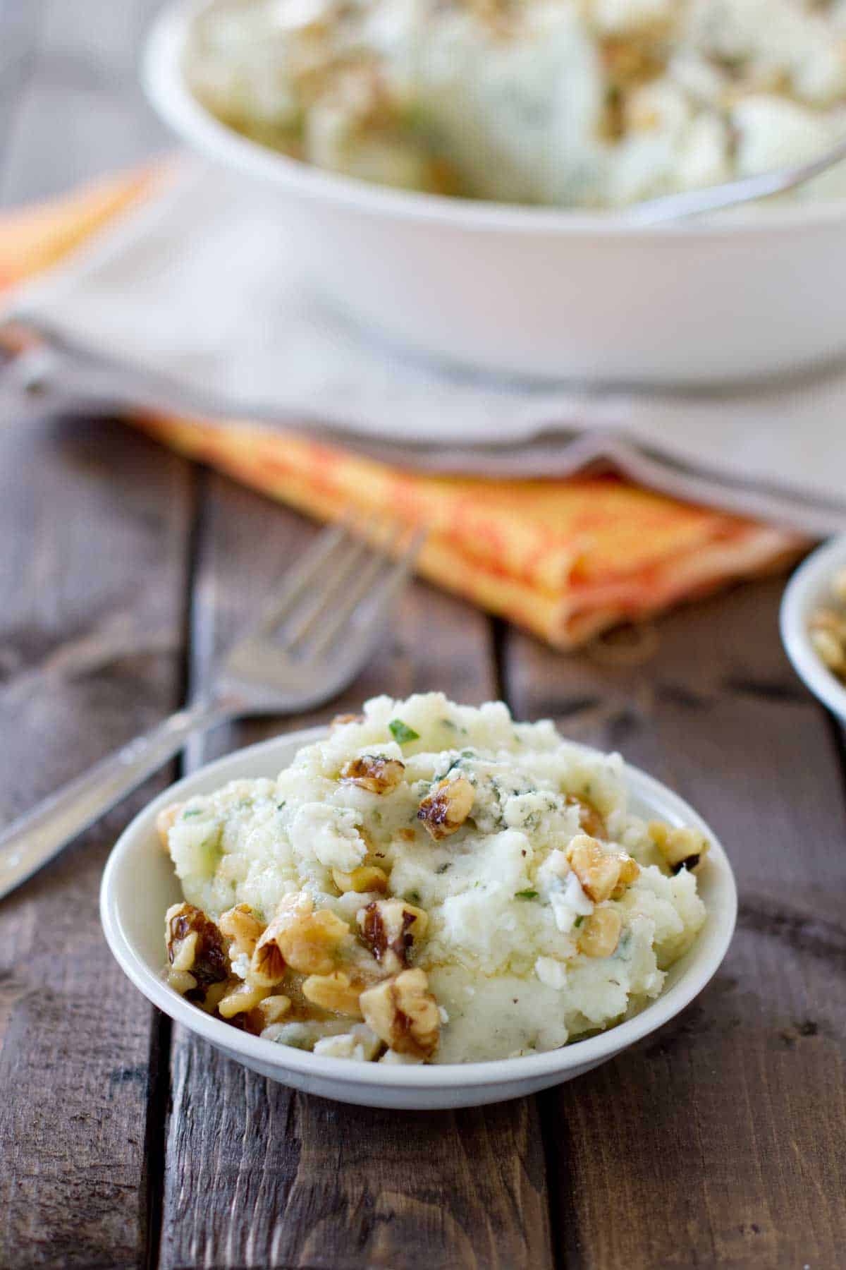 Small shallow bowl filled with Blue Cheese and Walnut Mashed Potatoes.