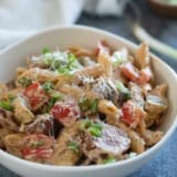 Bowl filled with Cajun Sausage Pasta topped with parmesan cheese.