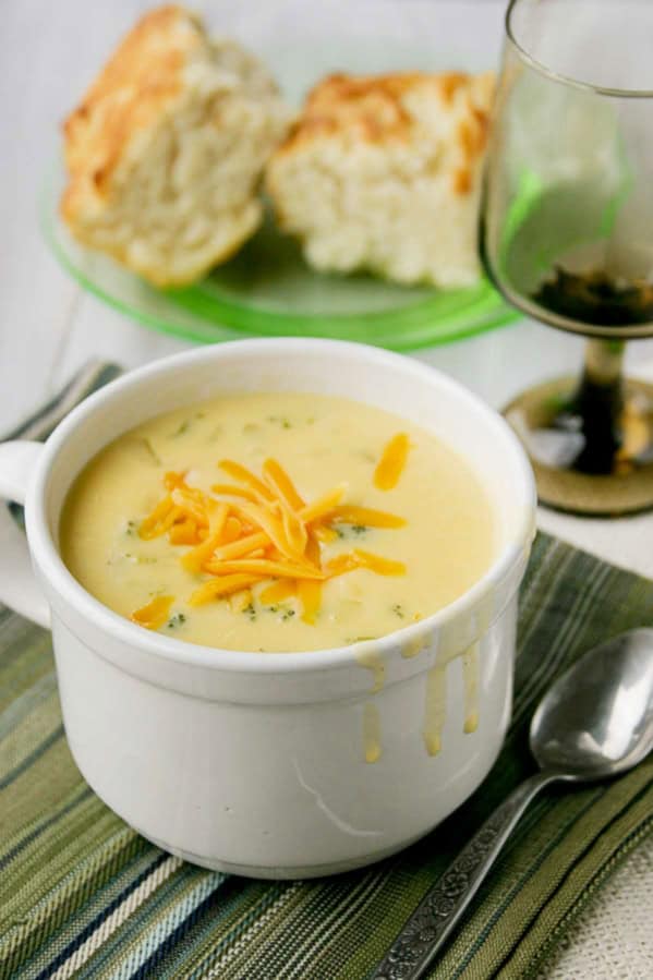 Bowl of cheesy vegetable chowder topped with cheddar cheese.