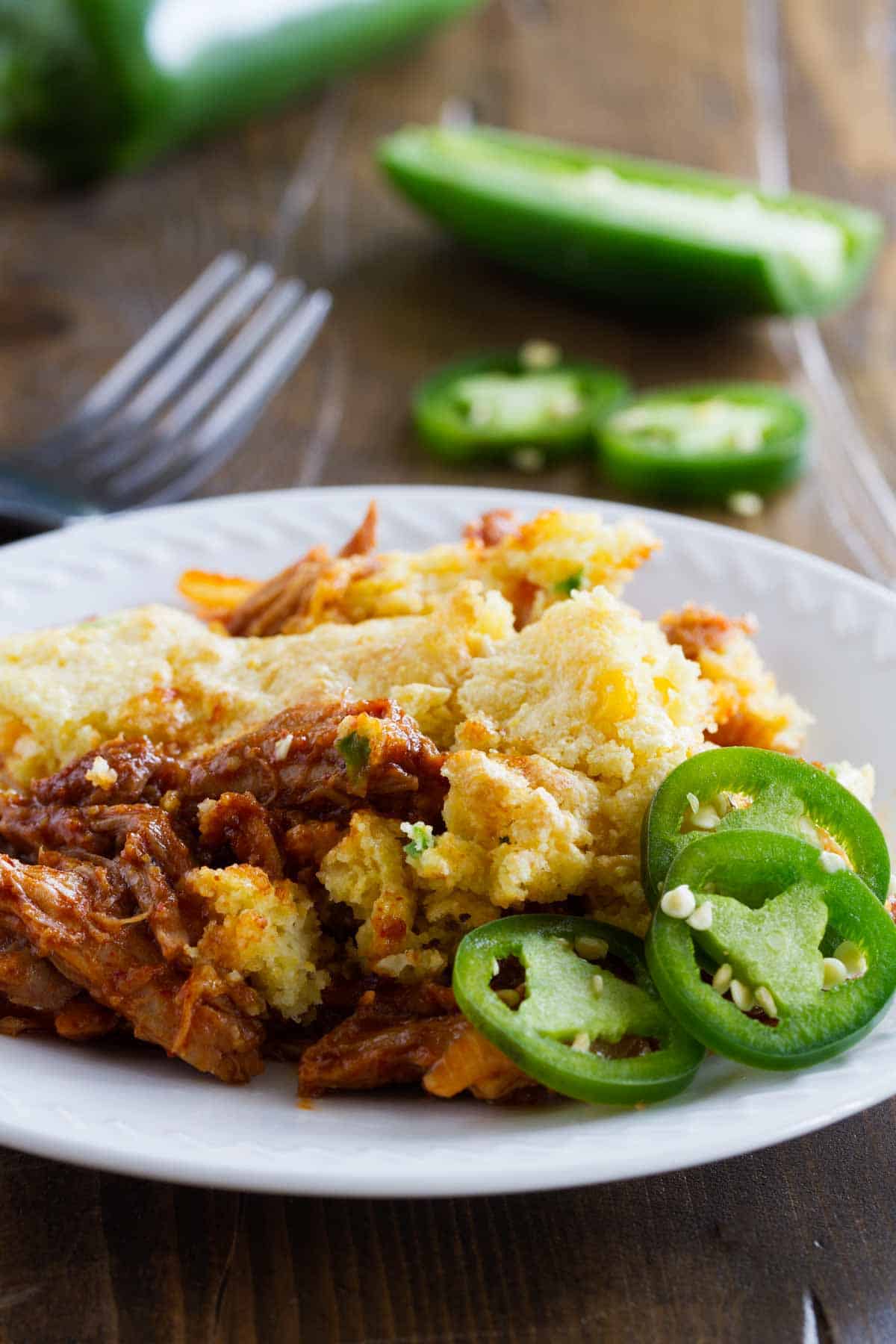 Serving of Cornbread Topped BBQ Pork on a plate with sliced jalapeños.