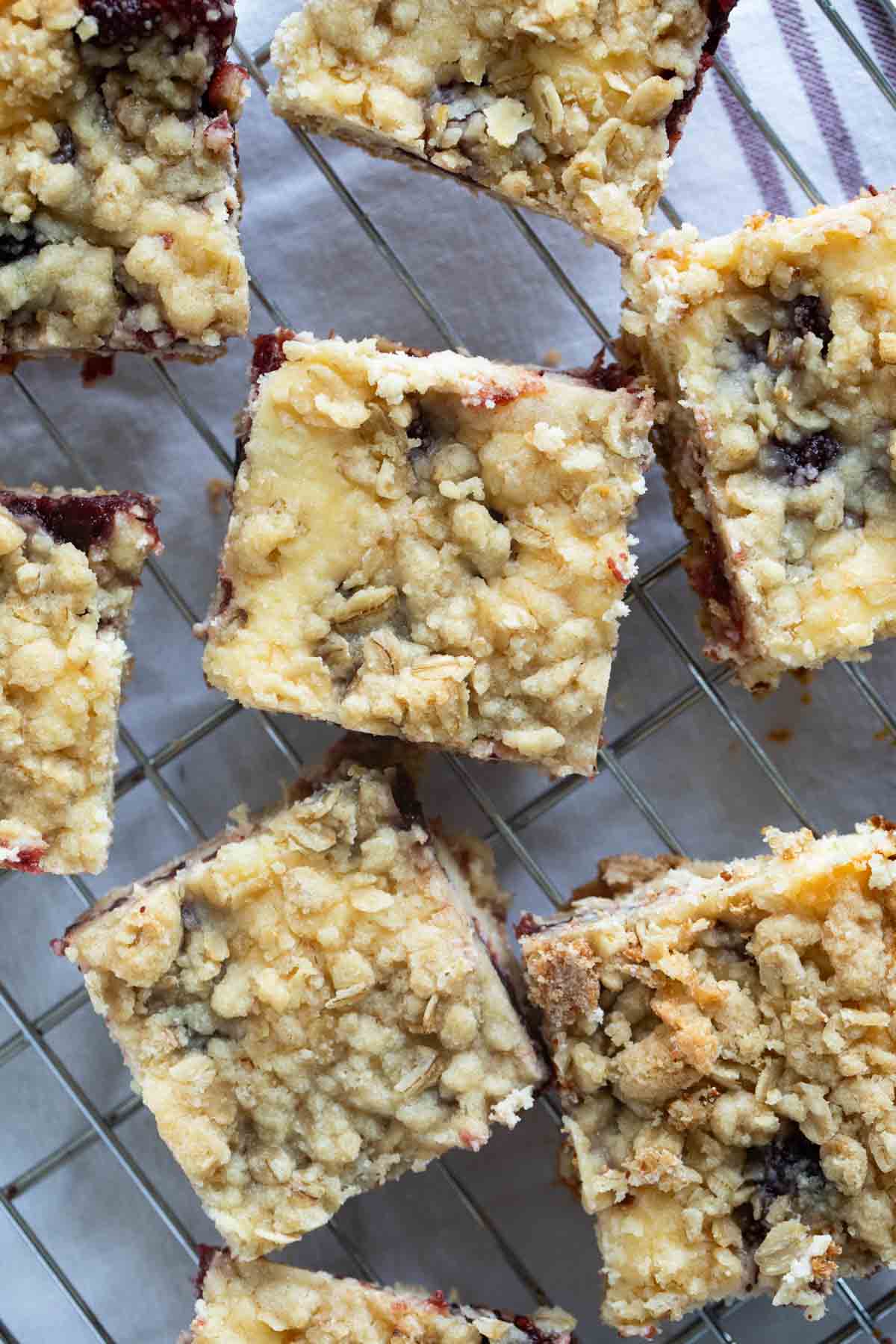 Sliced cranberry cheesecake bars cooling on a cooling rack.