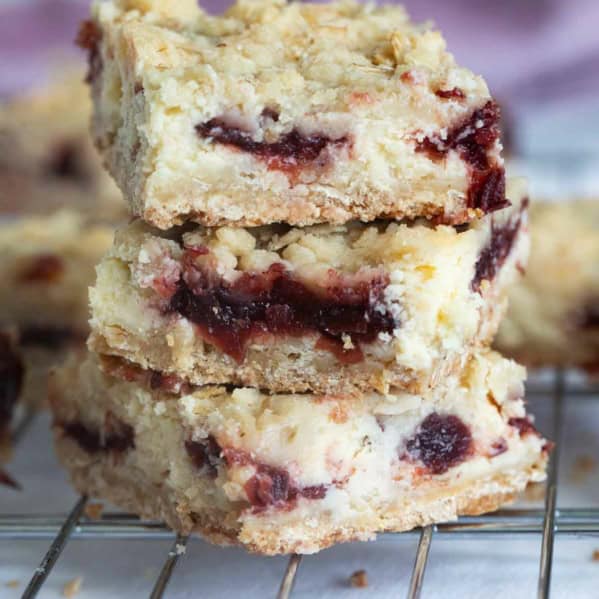 Three Cranberry Cheesecake Bars stacked on top of each other.