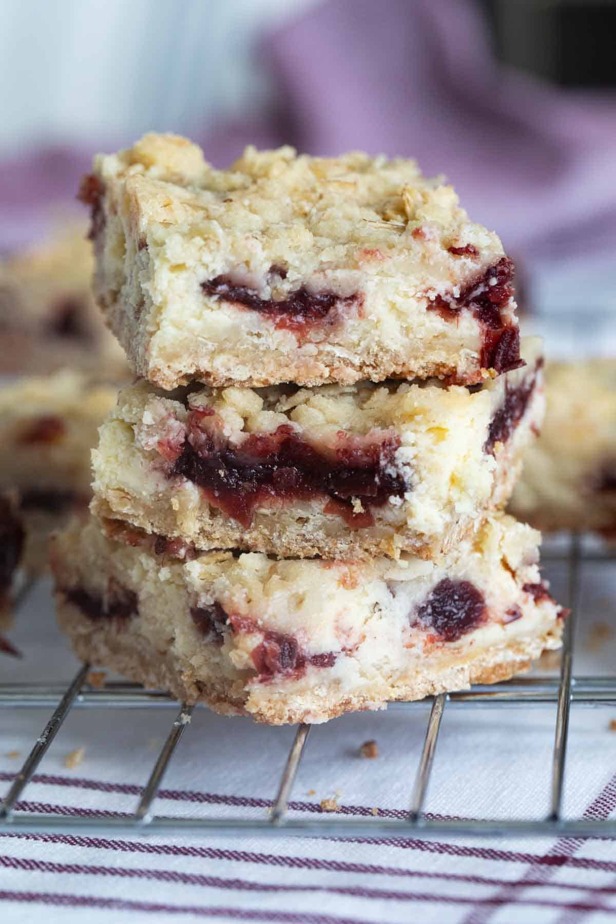 Three Cranberry Cheesecake Bars stacked on top of each other.