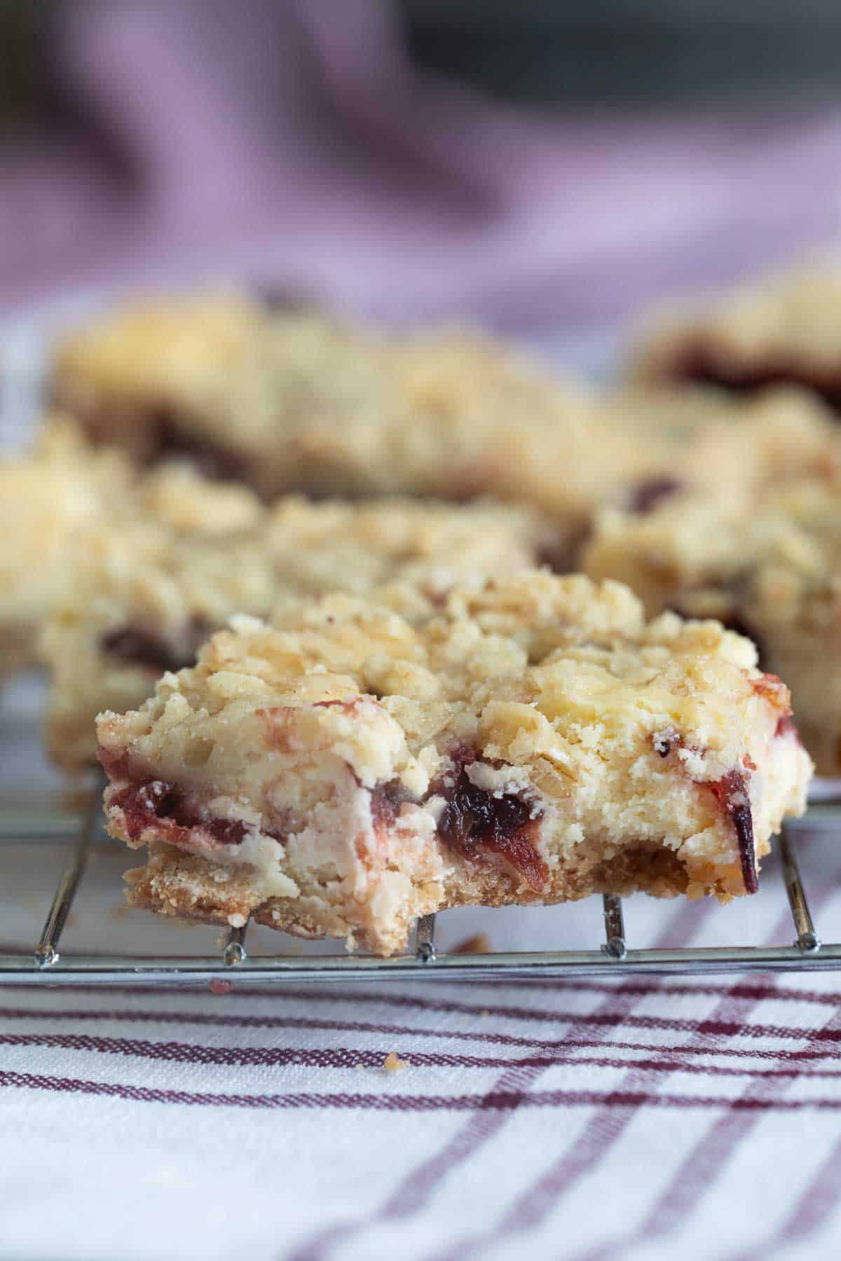 Cranberry Cheesecake Bar on a cooling rack with a bite taken from it.