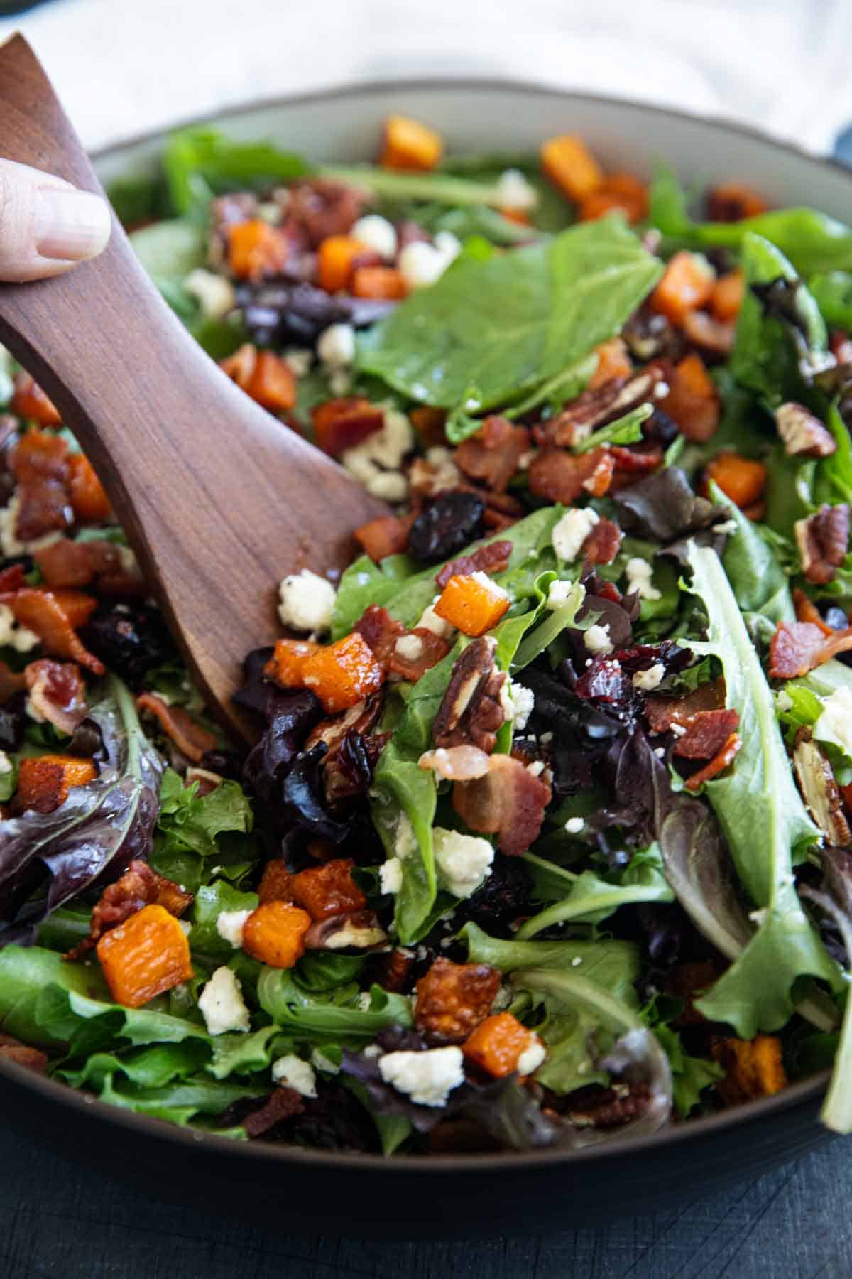 Dishing out Fall Harvest Salad with salad spoons.