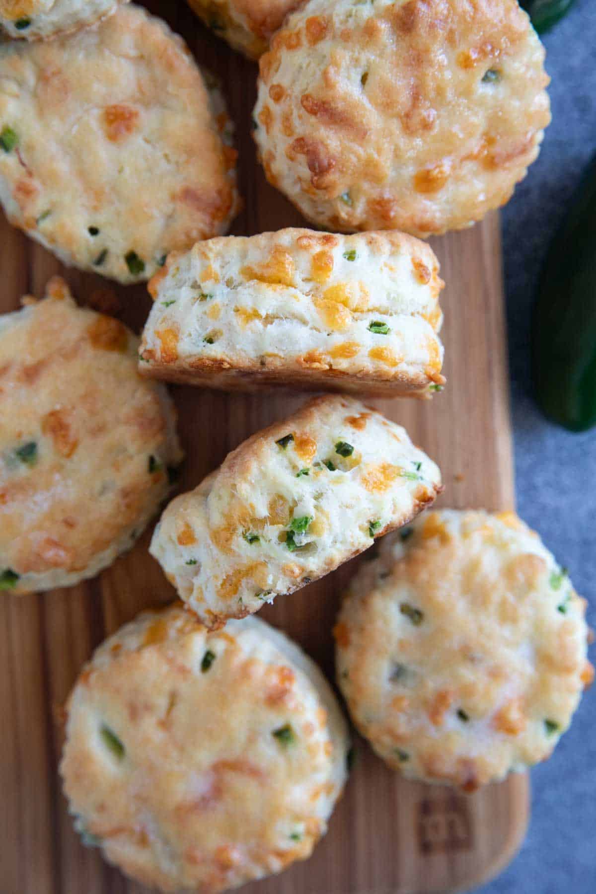 Jalapeño cheddar biscuits on a cutting board with two turned on their sides.