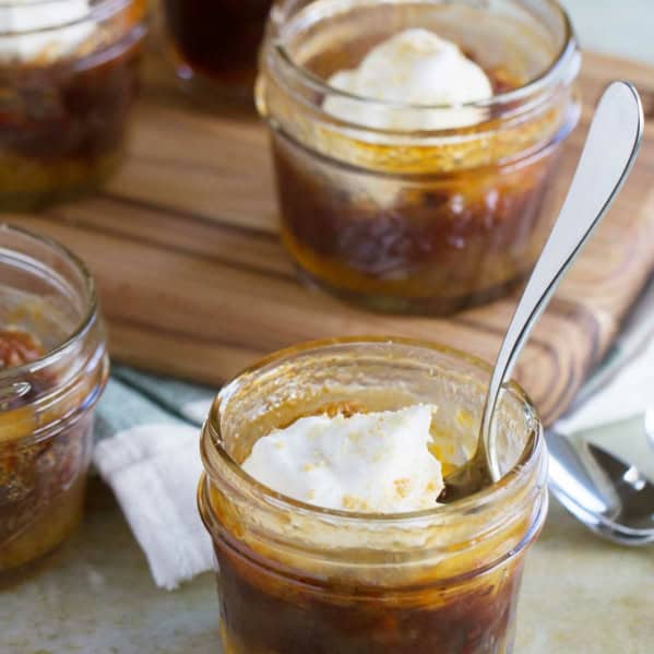 Mini Chocolate Pecan Pie in a jar, topped with whipped cream, with a spoon in one for serving.