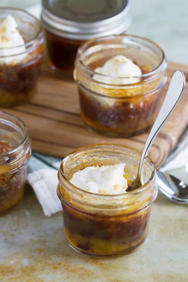 Mini Chocolate Pecan Pie in a jar, topped with whipped cream, with a spoon in one for serving.