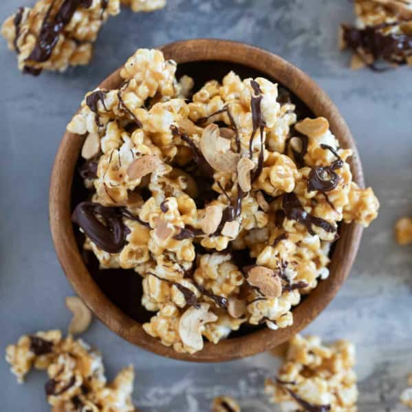 Wooden bowl filled with peanut butter, chocolate, and cashew popcorn.