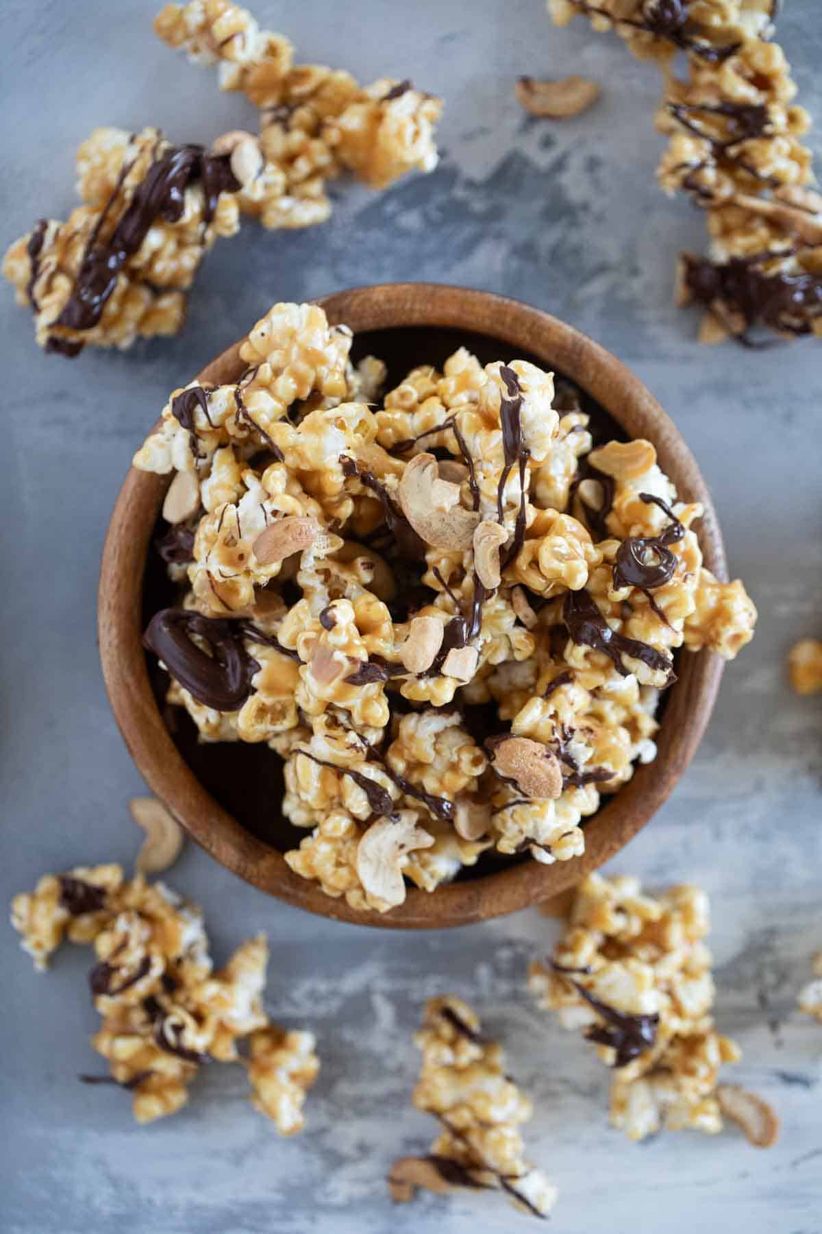 Wooden bowl filled with peanut butter, chocolate, and cashew popcorn.