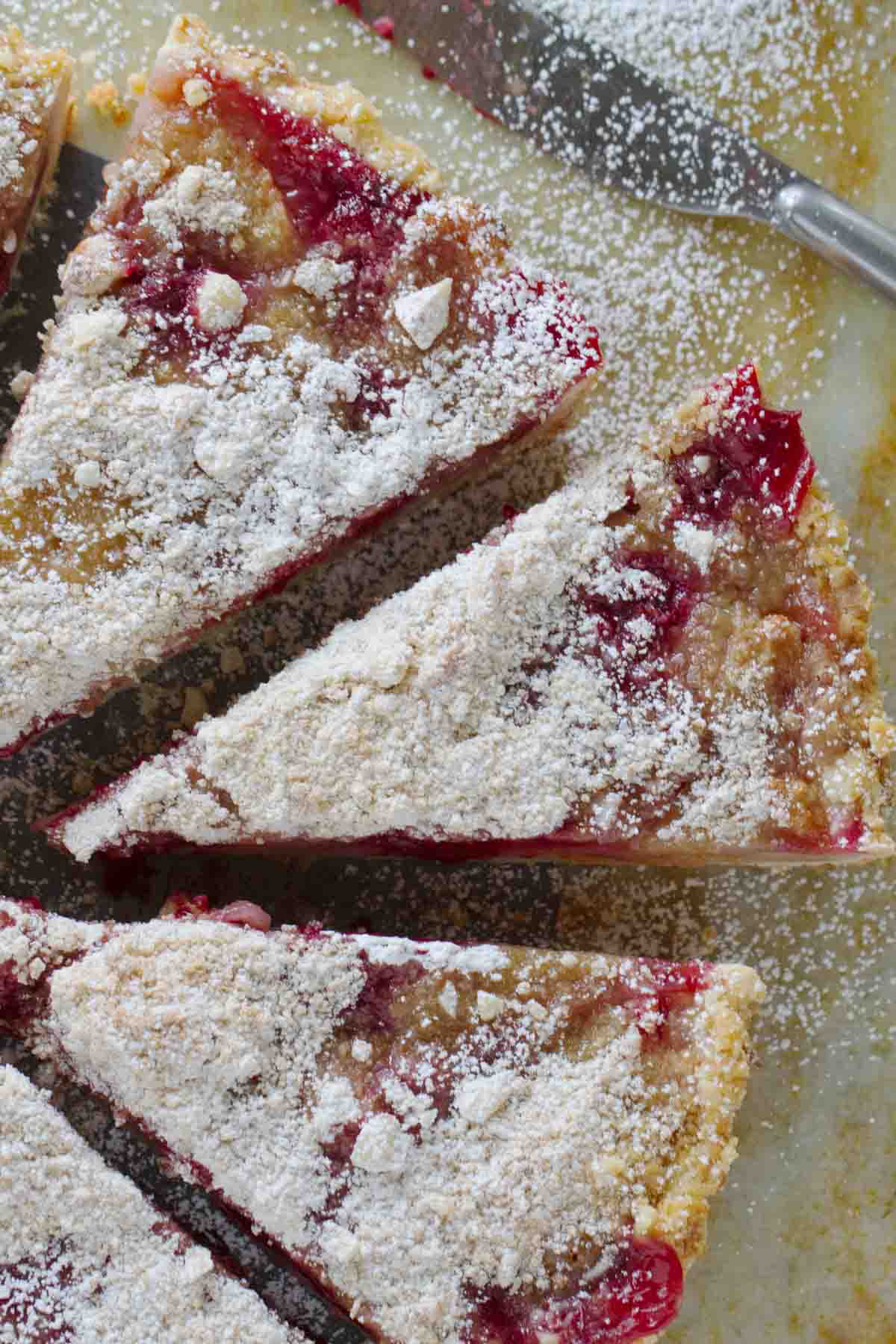 Pear and Raspberry Tart sprinkled with powdered sugar and cut into slices.