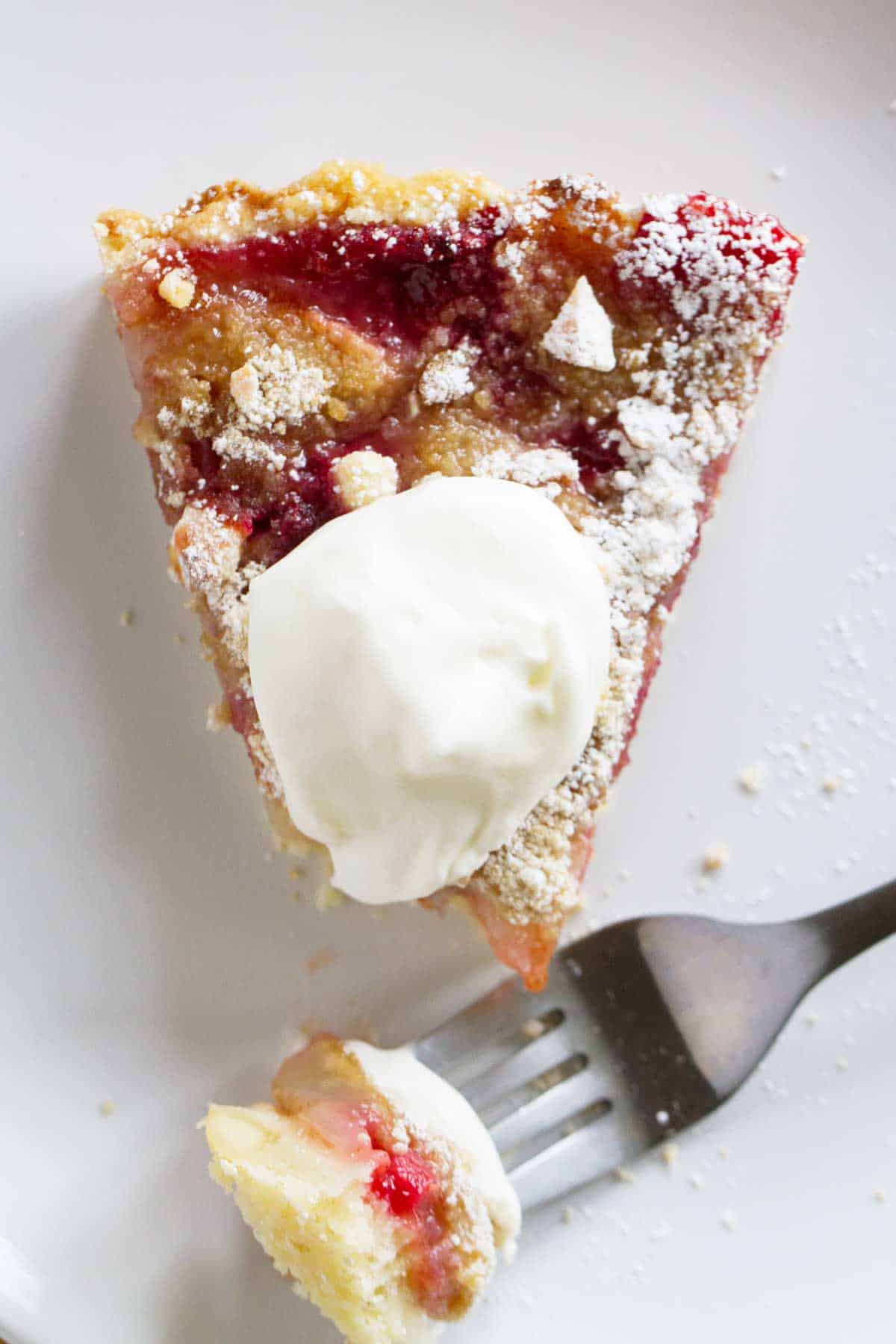 Slice of Pear and Raspberry Tart topped with whipped cream.