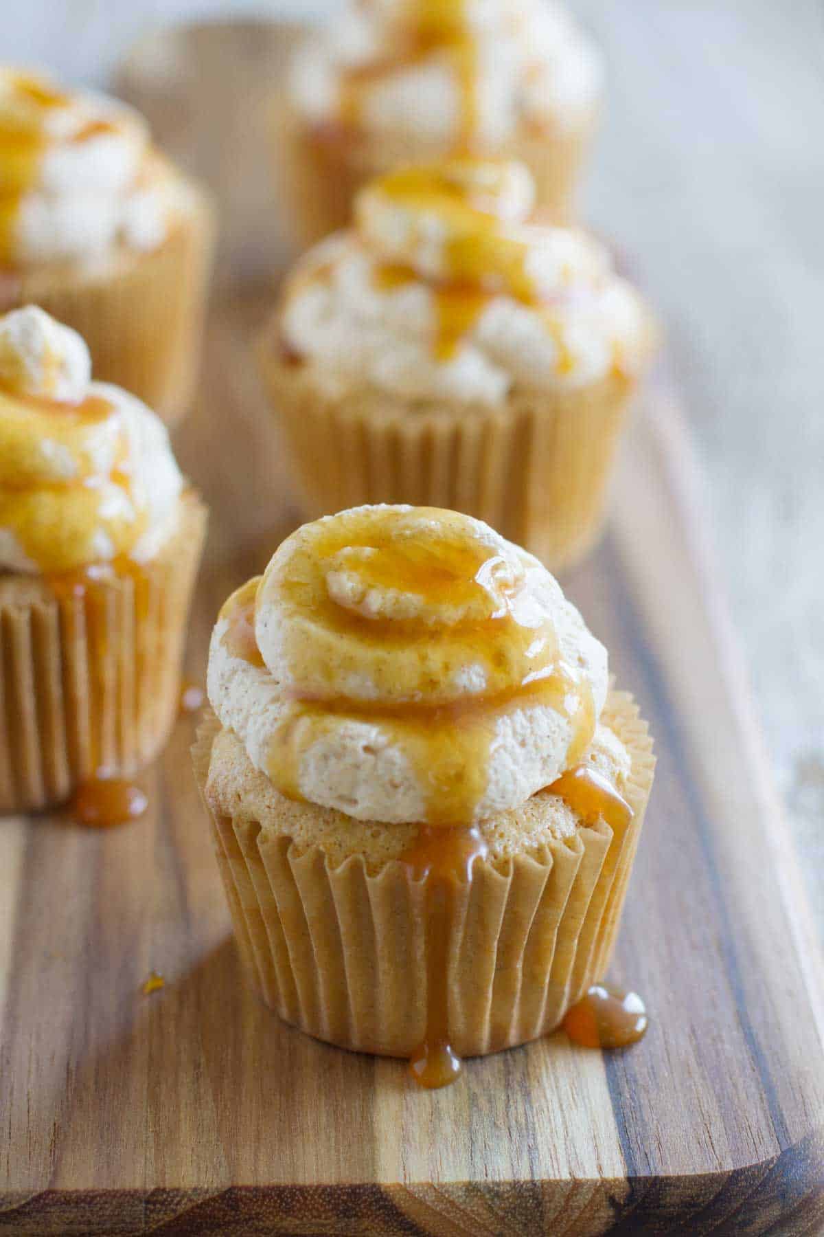 Pumpkin Angel Food Cupcakes topped with spiced whipped cream and caramel sauce.