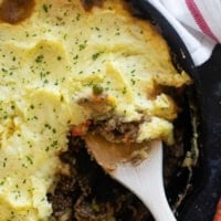 Cast iron skillet with Shepherd's Pie with aa wooden spoon.