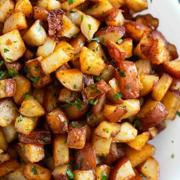 Oven roasted Breakfast Potatoes with spices sprinkled with fresh parsley on a plate.