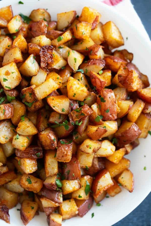 Oven roasted Breakfast Potatoes with spices sprinkled with fresh parsley on a plate.