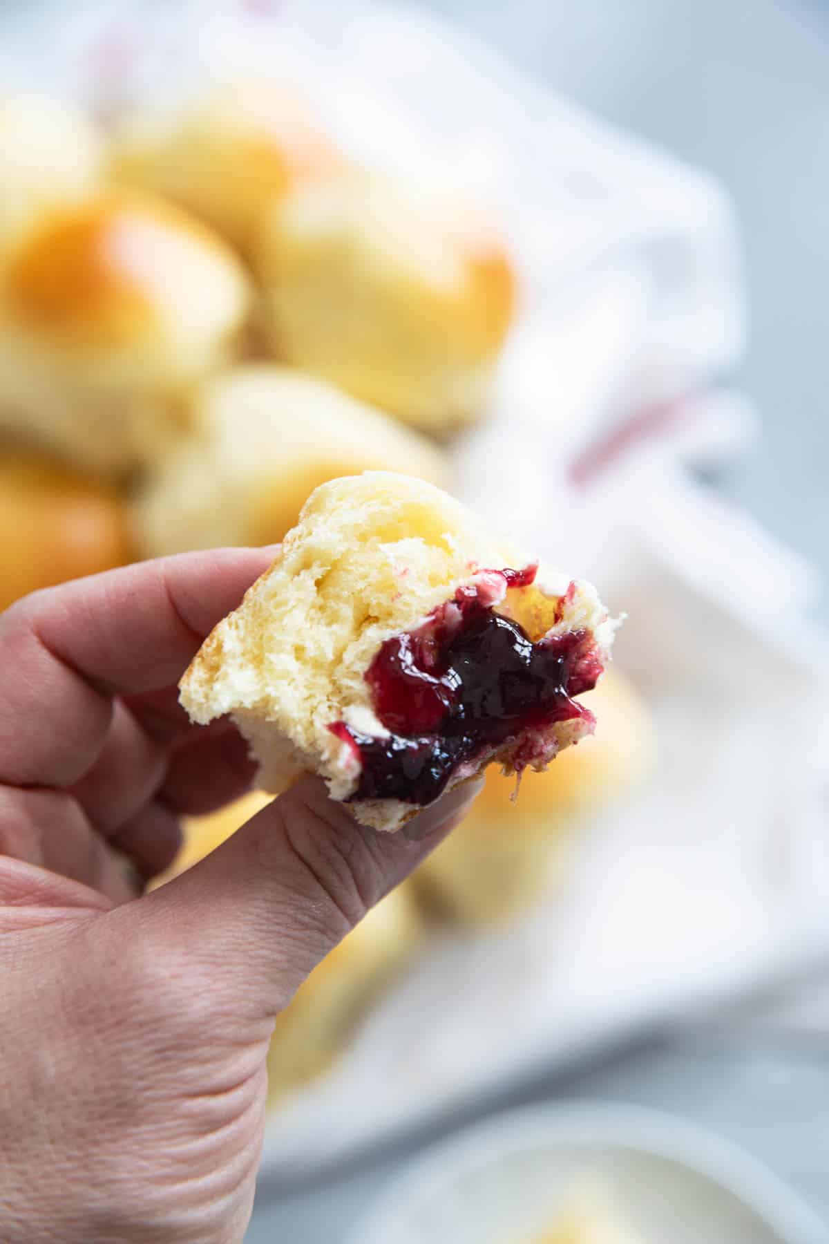 Brioche Roll with jam and butter being held.