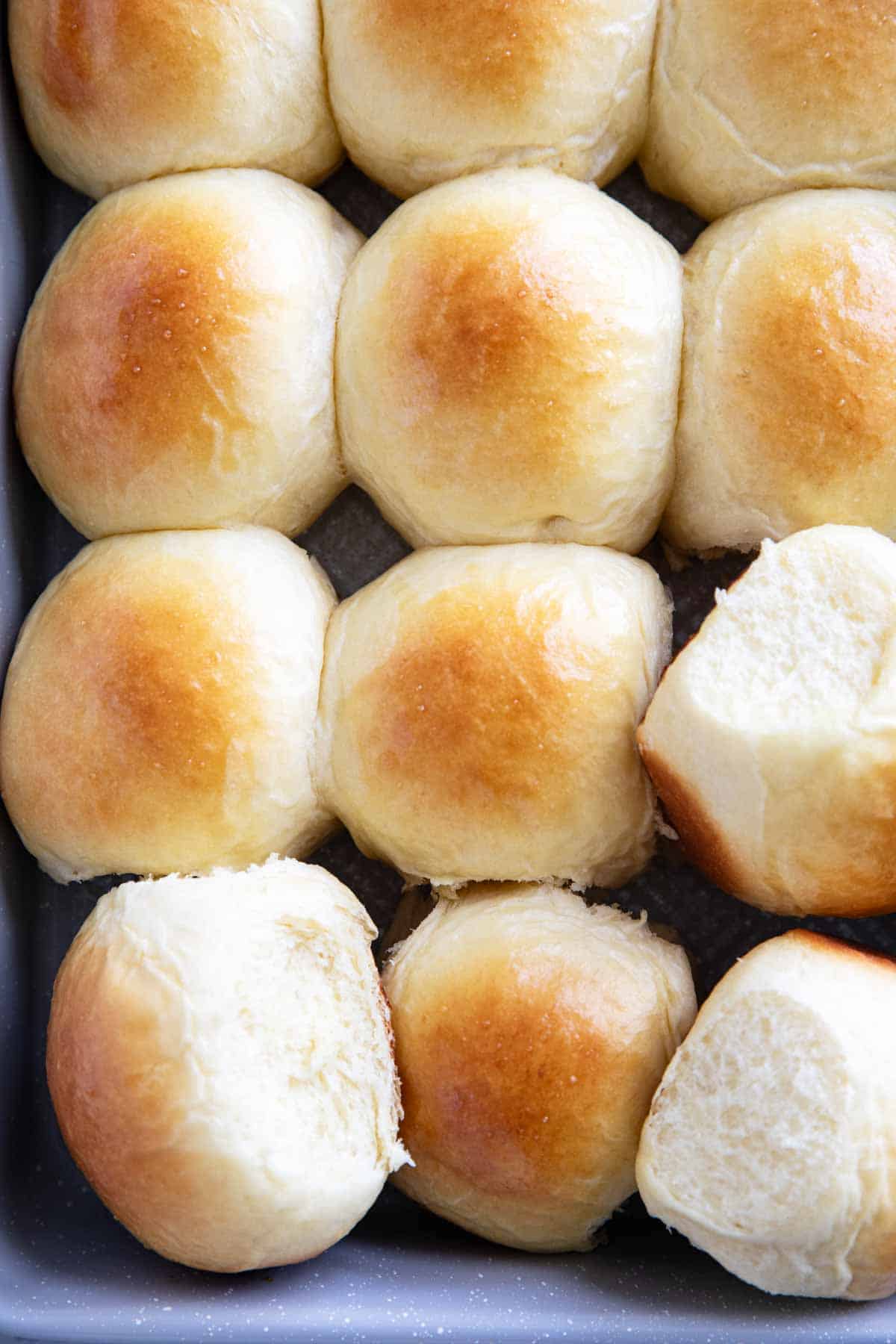 Brioche Rolls in a pan with a few turned to the side.