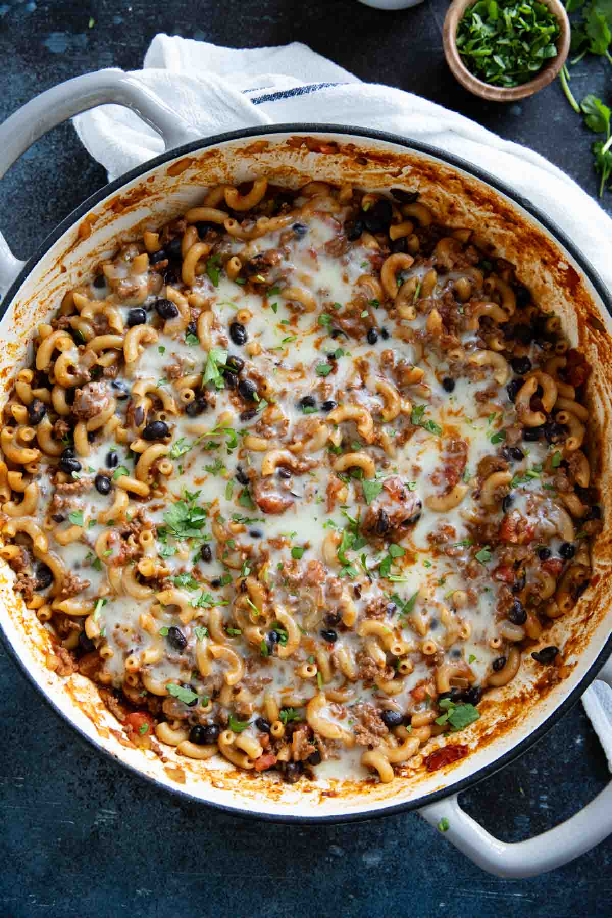 Casserole dish filled with Chili Mac, topped with cheese and cilantro.