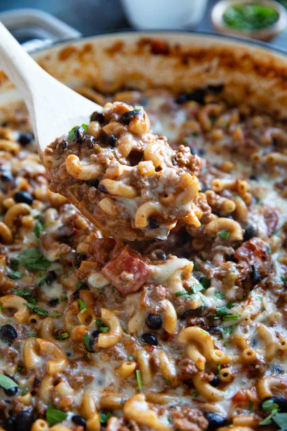 Scooping Chili Mac out of a casserole dish.