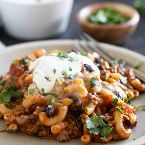 Serving of Chili Mac on a plate, topped with sour cream.