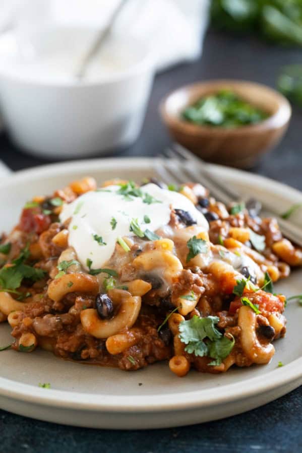 Serving of Chili Mac on a plate, topped with sour cream.