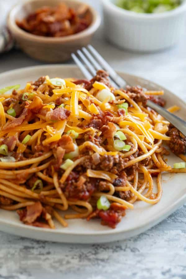 Plate of Cowboy Spaghetti with ground beef, bacon, cheese, and green onions.