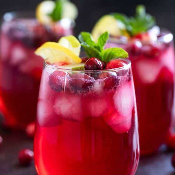 Three virgin Cranberry Spritzers with fresh lemon and lime.