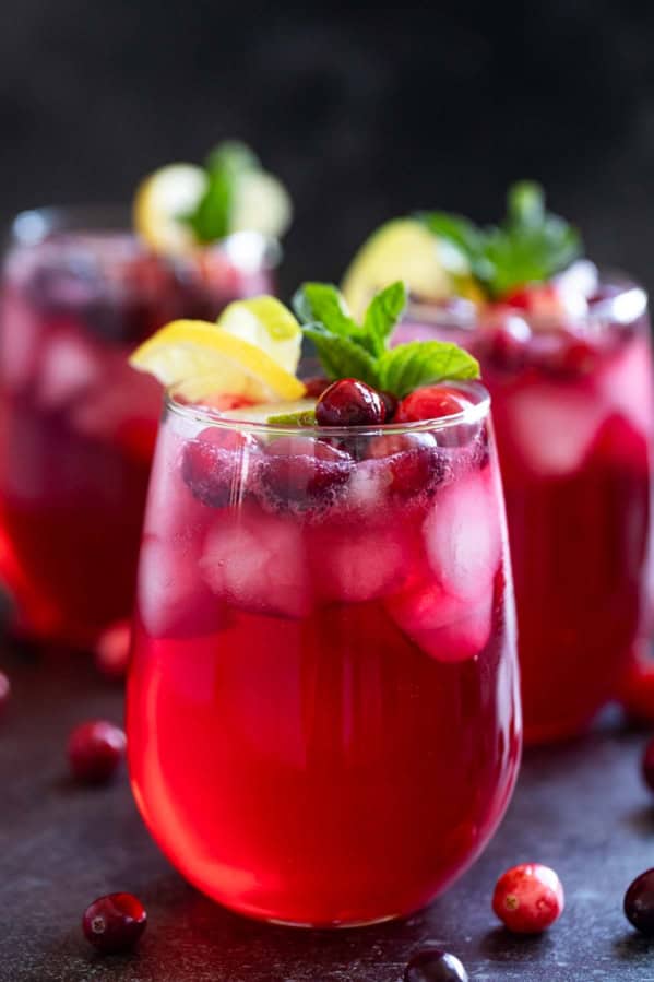 Three virgin Cranberry Spritzers with fresh lemon and lime.