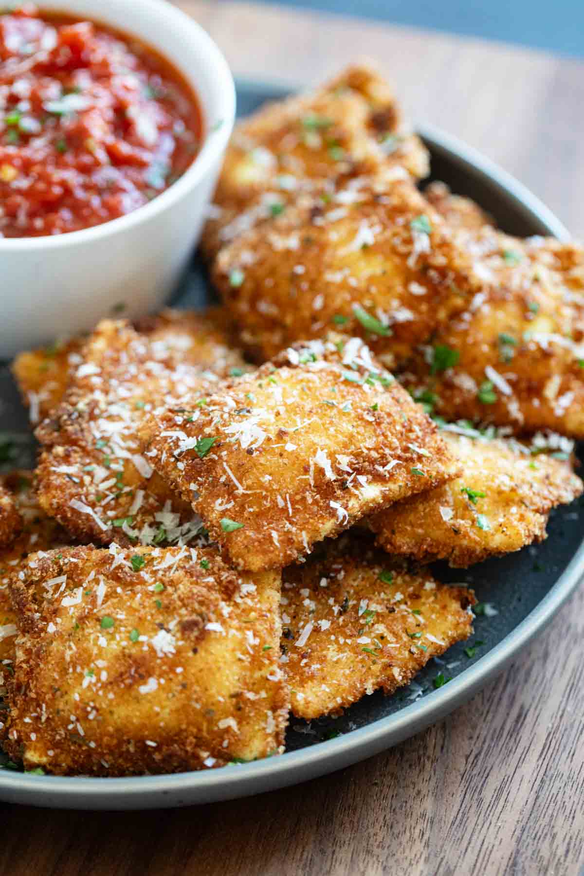 Fried Ravioli on a plate, sprinkled with parmesan and parsley.