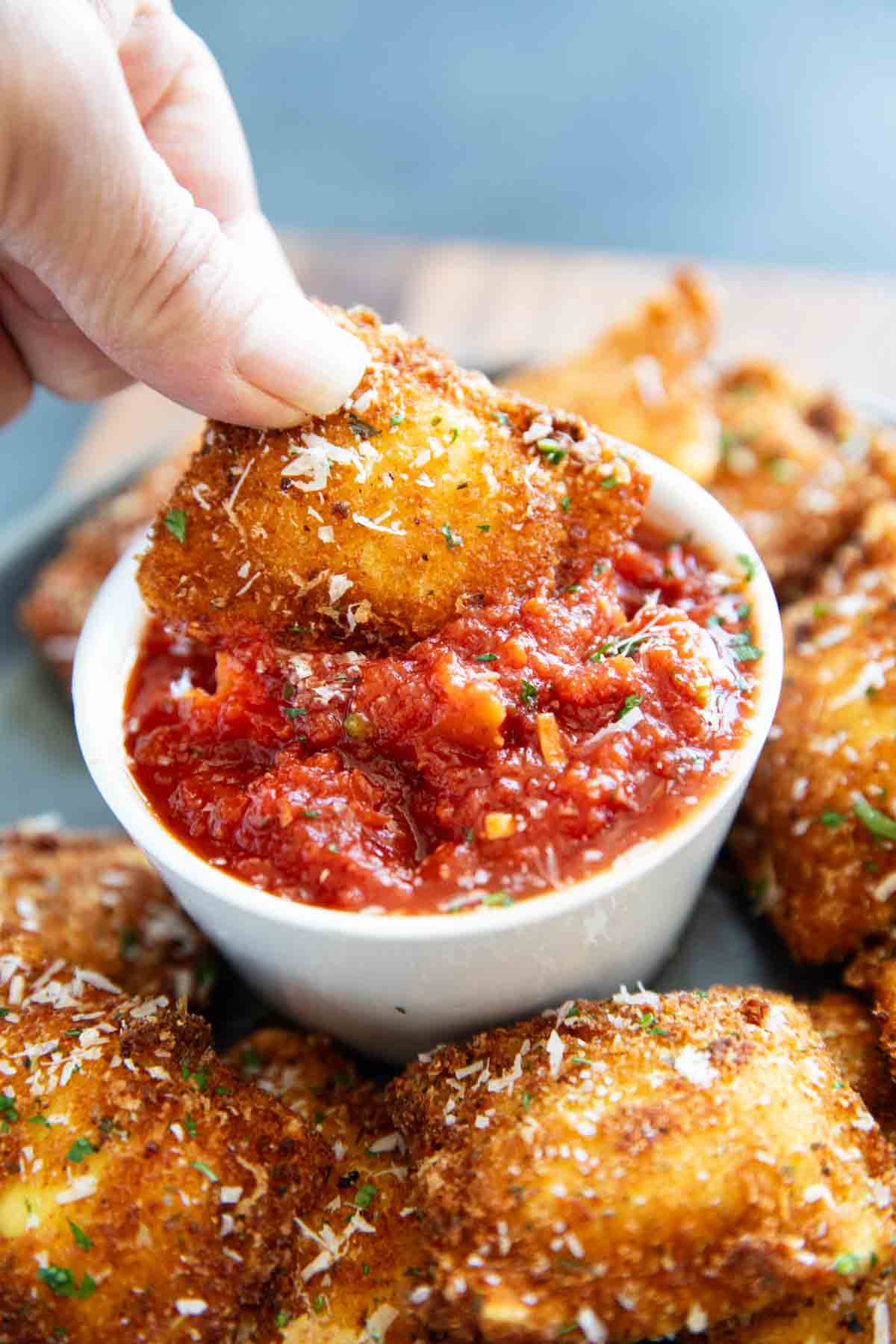 Dipping a fried ravioli into marinara sauce.