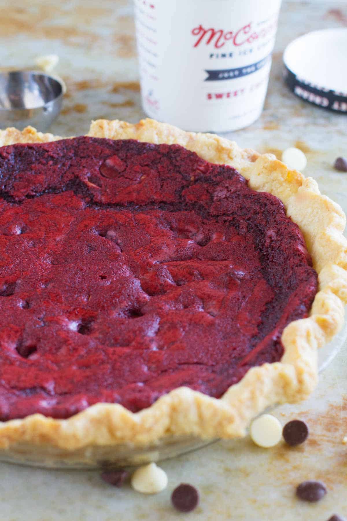 Full red velvet cookie pie with a pint of ice cream in the background.