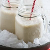 Two jars filled with root beer float smoothie, each with a straw.