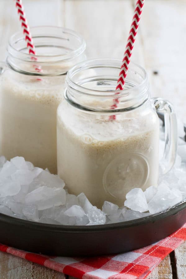 Two jars filled with root beer float smoothie, each with a straw.