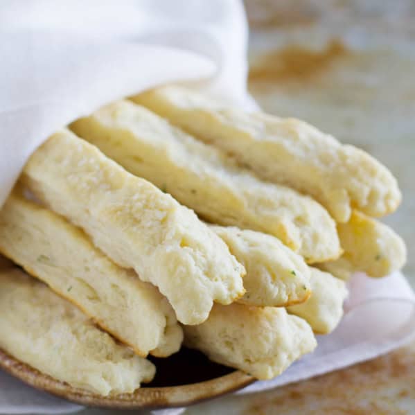 Sour cream breadsticks wrapped in a towel on a plate.