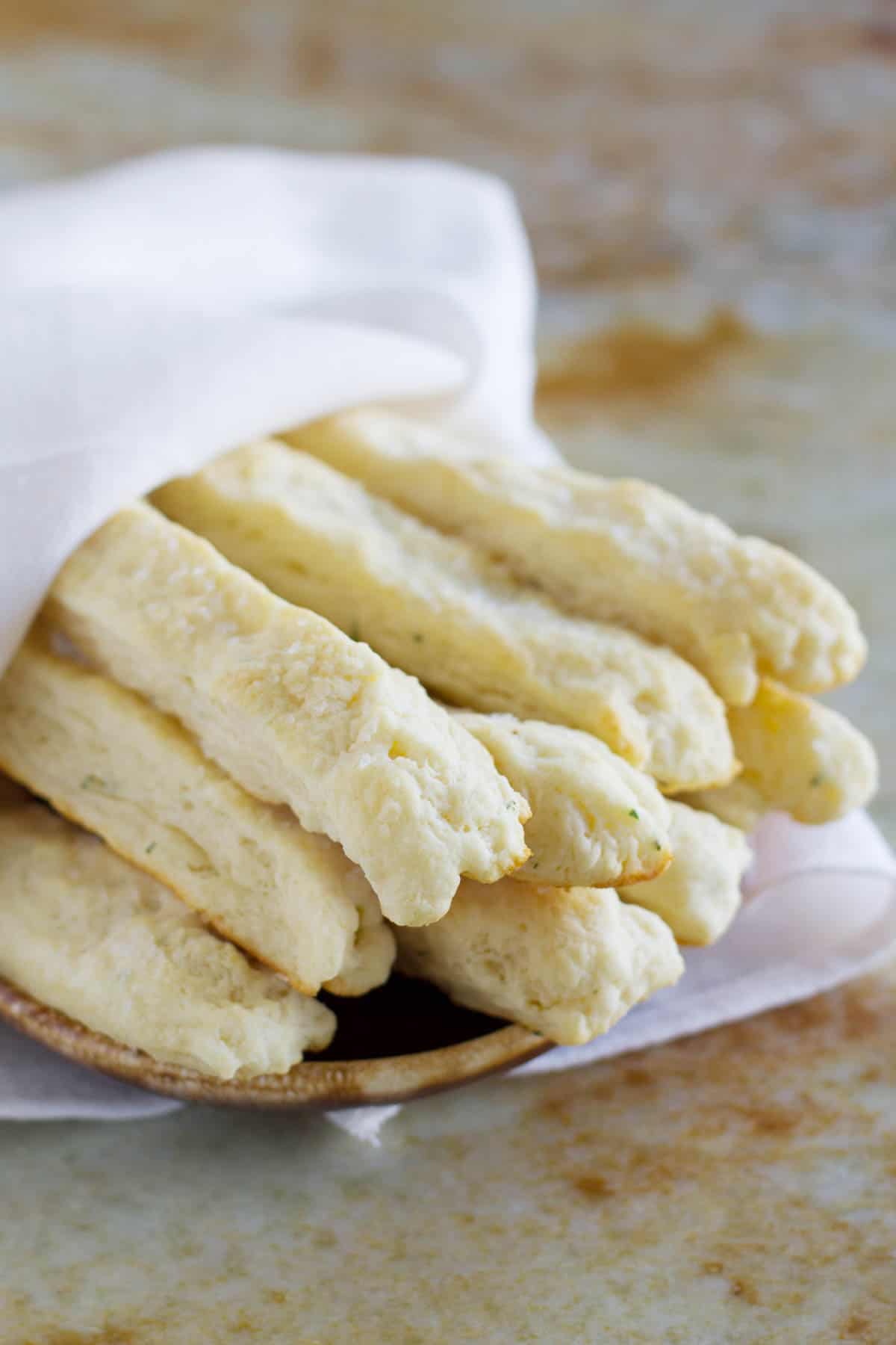 Sour cream breadsticks wrapped in a towel on a plate.