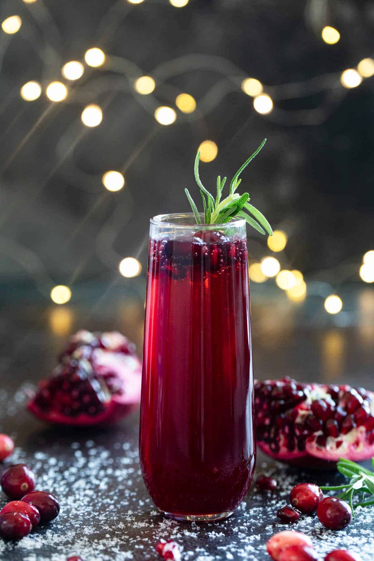 Single Virgin Pomegranate and Cranberry Bellini with fresh pomegranate and cranberries surrounding it.